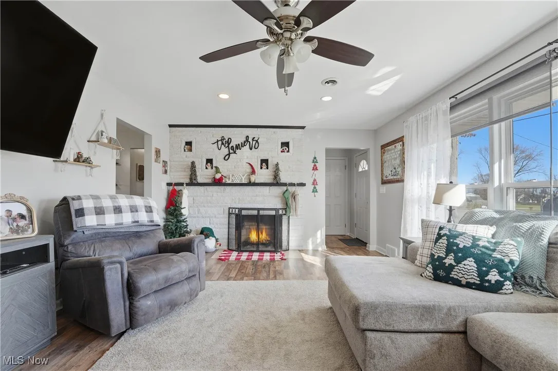 Living room with wood finished floors, a fireplace, and recessed lighting