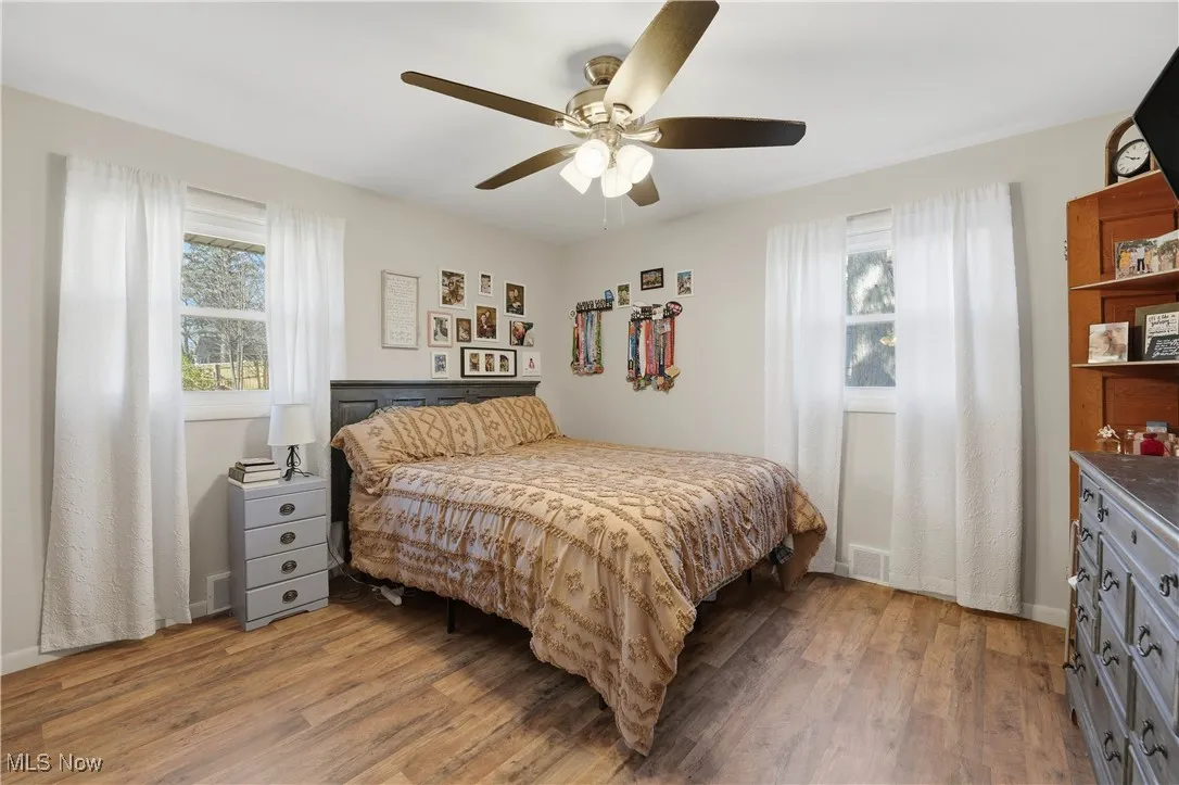 Bedroom featuring multiple windows, light wood-type flooring, and ceiling fan
