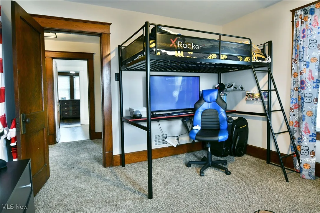 Carpeted bedroom with baseboards and a desk