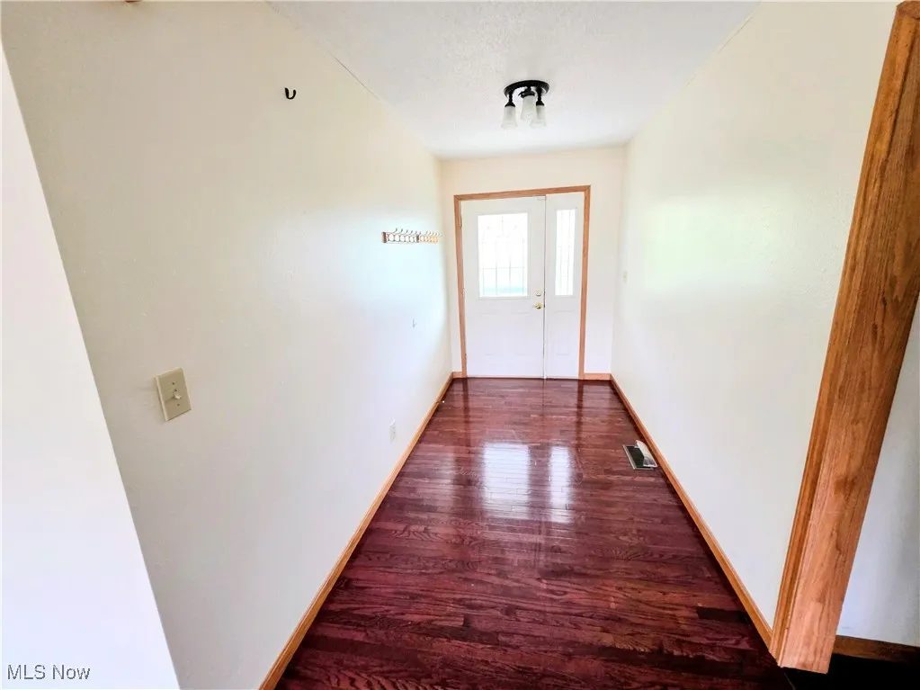 Doorway with wood finished floors and baseboards