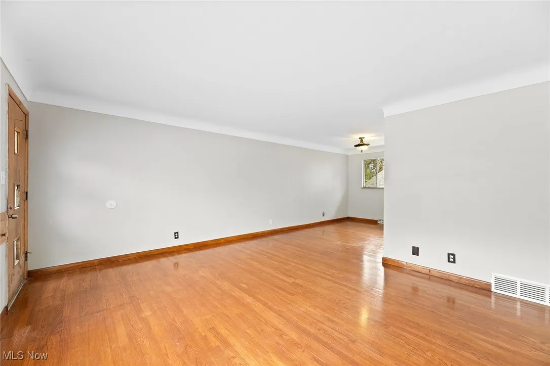 Living room featuring light wood finished floors and baseboards and a view of the dining room.