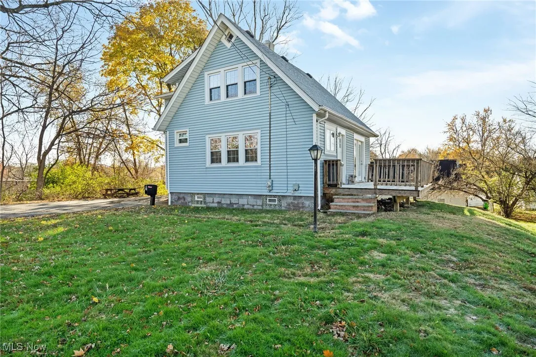 View of side of property with a yard and a wooden deck