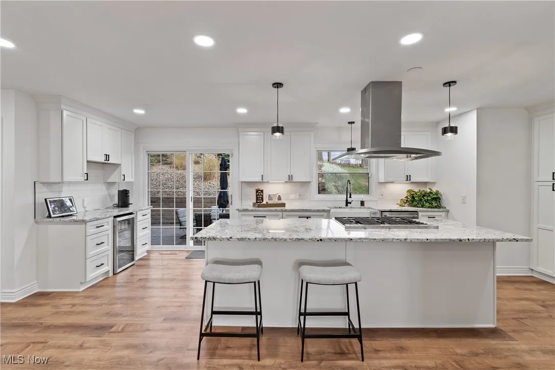 Kitchen featuring backsplash, white cabinets, recessed lighting, hanging light fixtures, and light stone counters