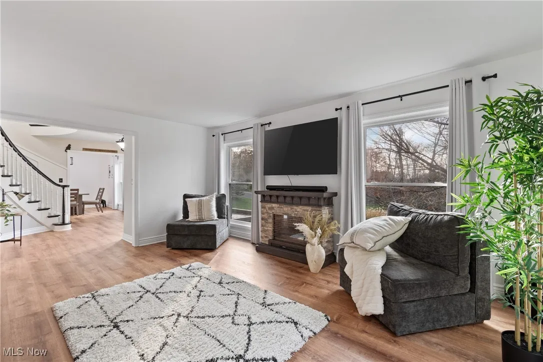 Living area with light wood finished floors, stairs, and a fireplace