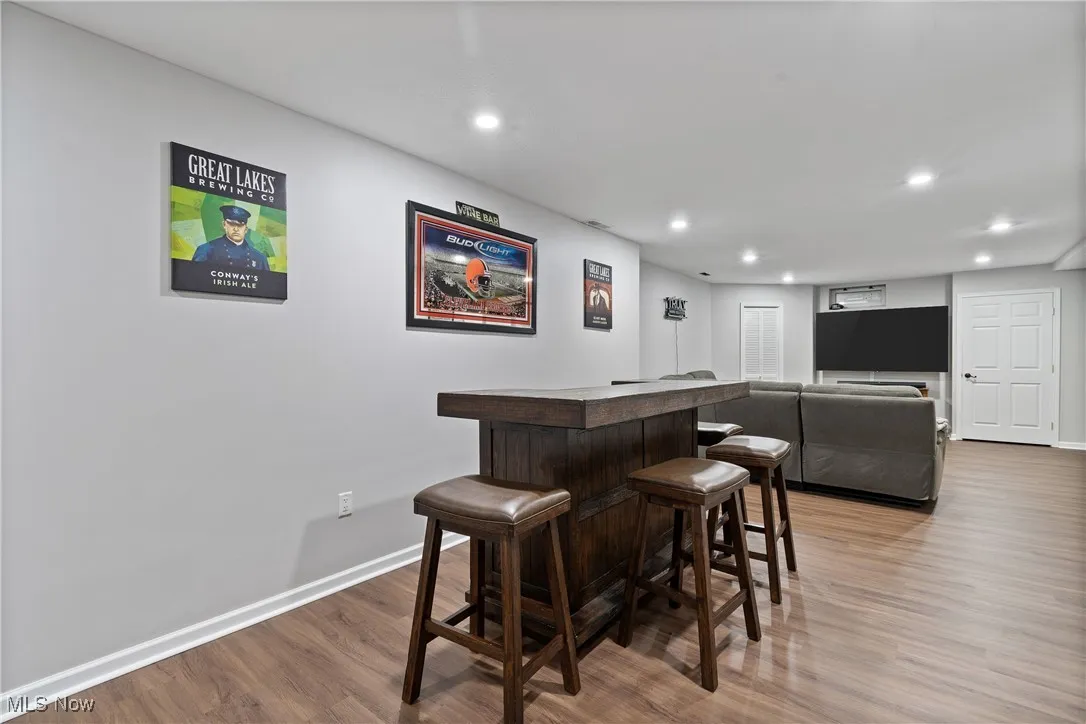 Indoor dry bar with light wood-style floors, recessed lighting, and dark countertops