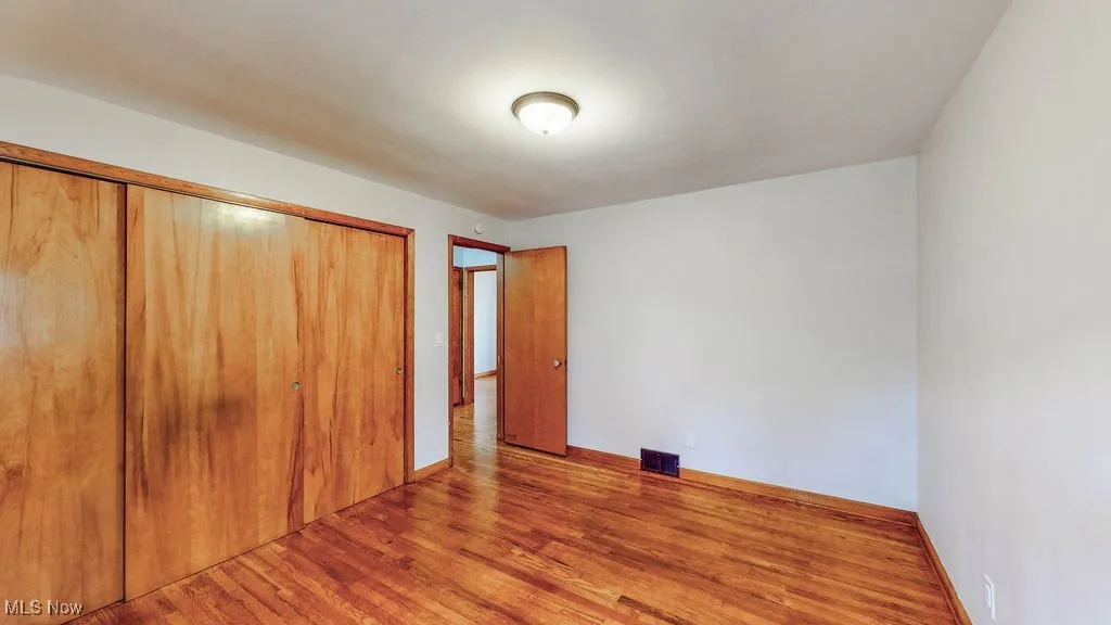 Unfurnished bedroom with wood finished floors and a large closet