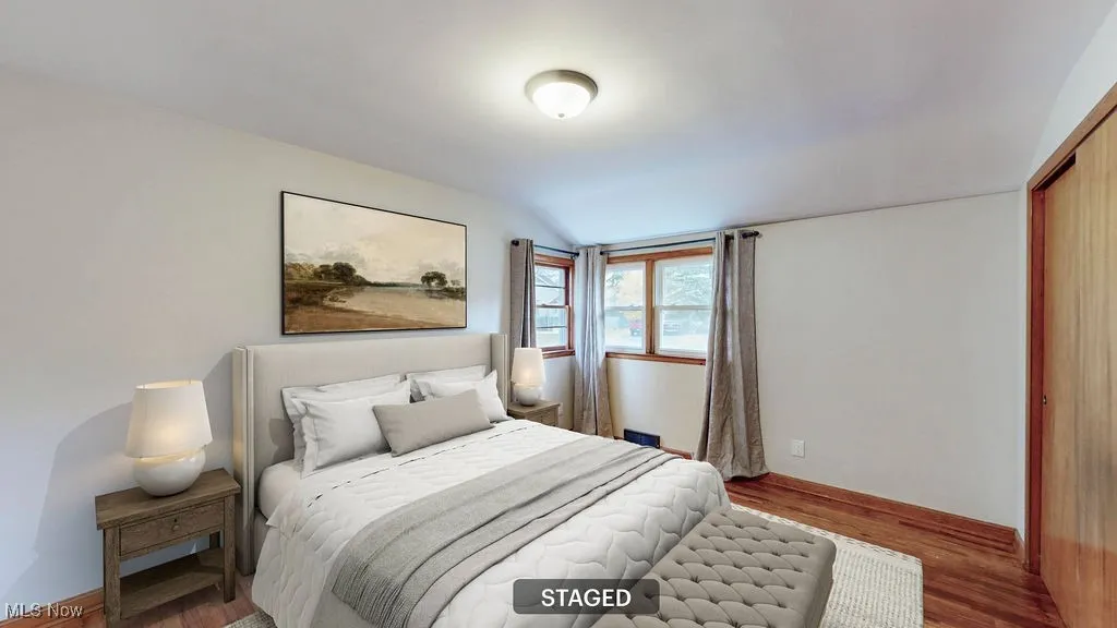 Virtually staged bedroom with wood finished floors and a closet