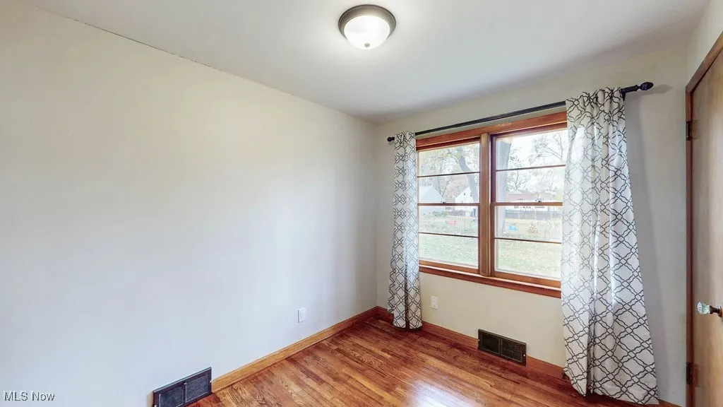 Unfurnished bedroom featuring wood finished floors and baseboards