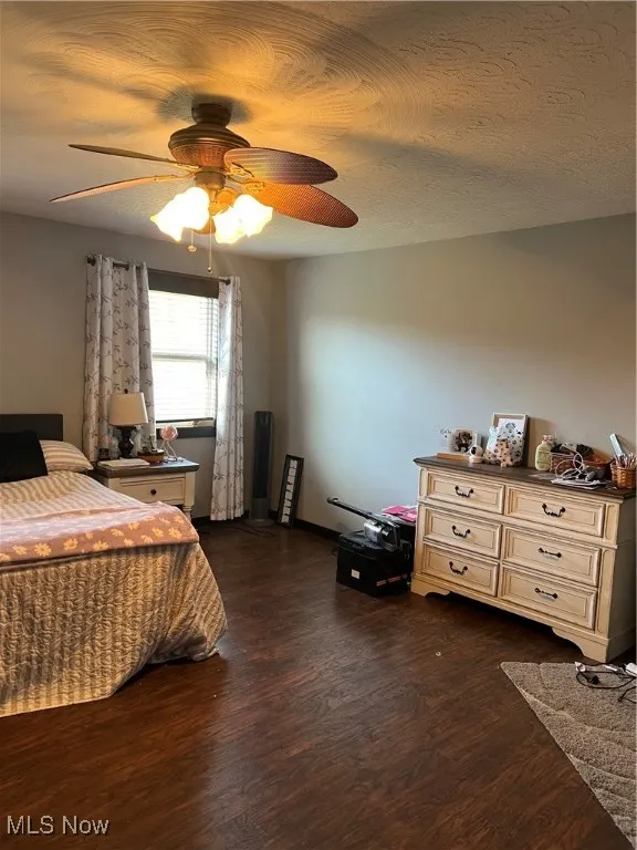 Bedroom featuring dark wood finished floors, ceiling fan, and a textured ceiling