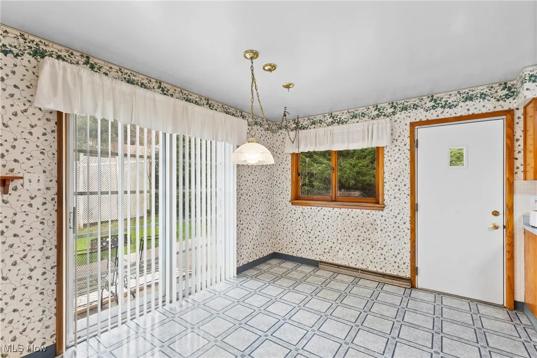 Unfurnished dining area featuring wallpapered walls and light tile patterned floors
