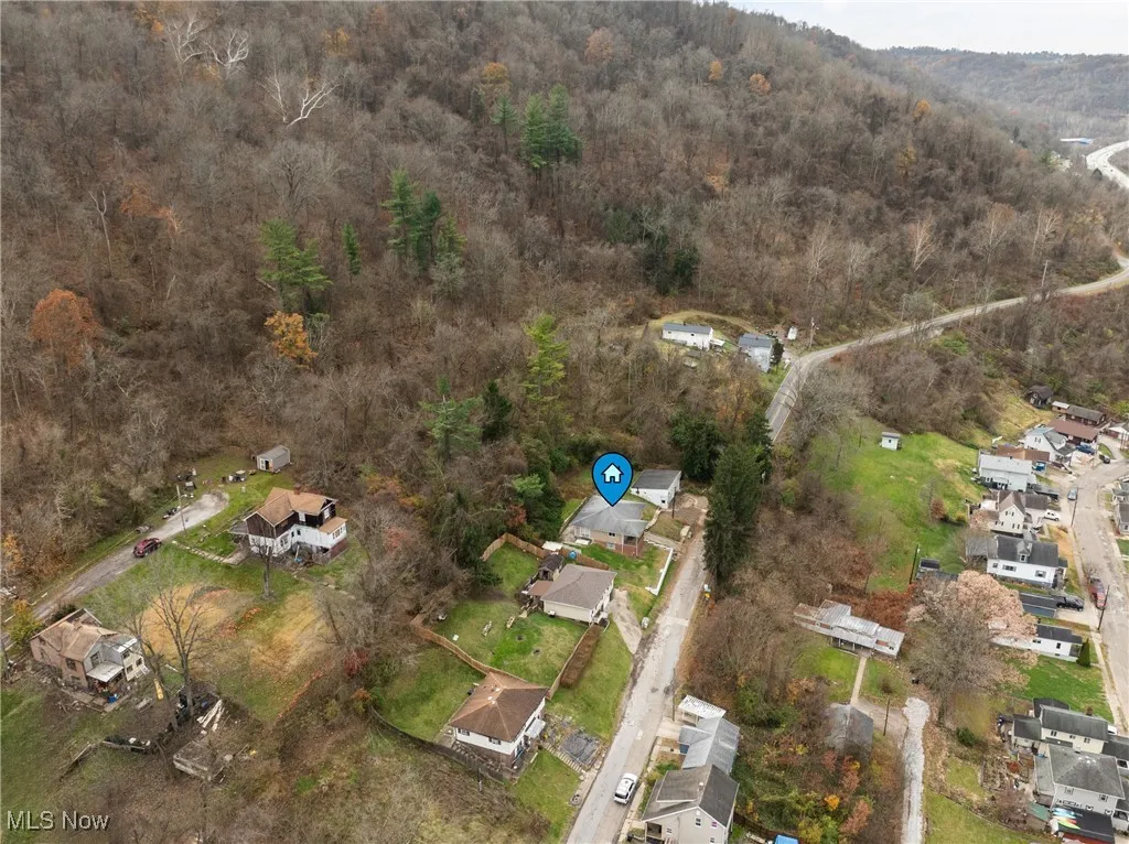 Aerial view of property's location with nearby suburban area and a forest