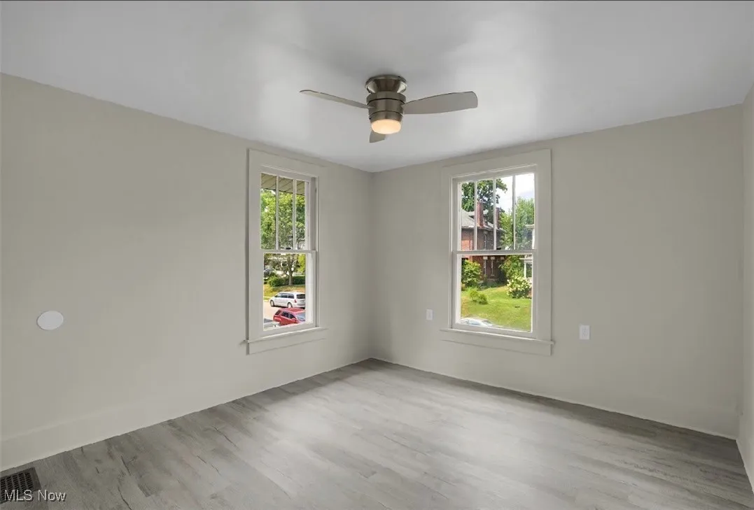 Unfurnished room featuring light wood-style floors, plenty of natural light, and a ceiling fan