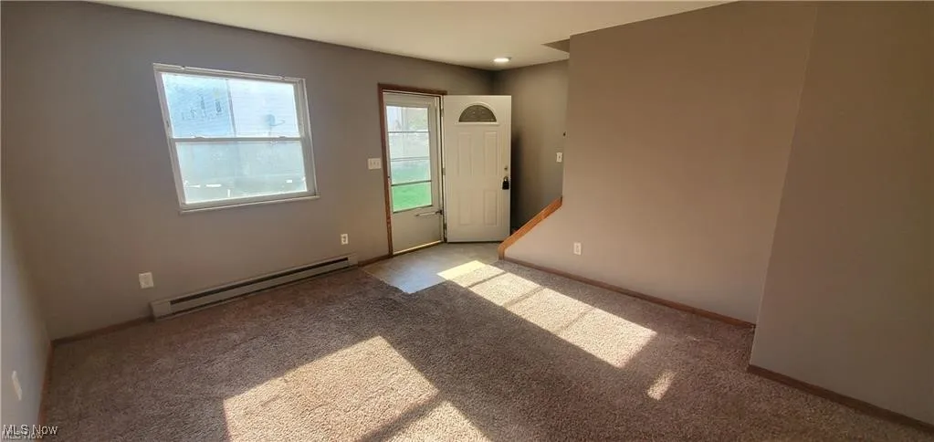 Empty room featuring a baseboard radiator and carpet