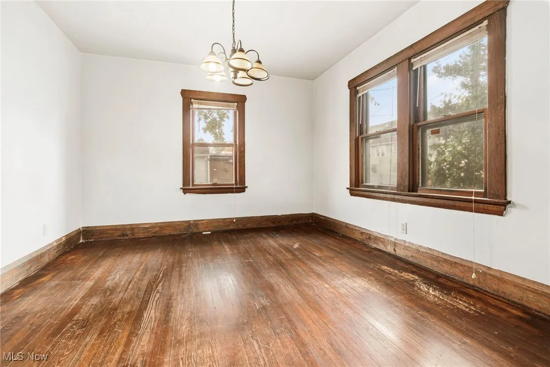 Empty room featuring dark wood-style flooring and a chandelier