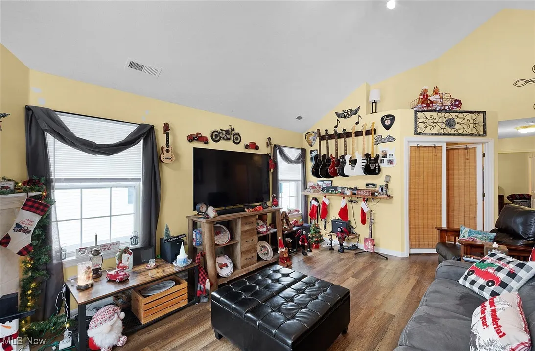 Living room featuring wood finished floors, plenty of natural light, and high vaulted ceiling