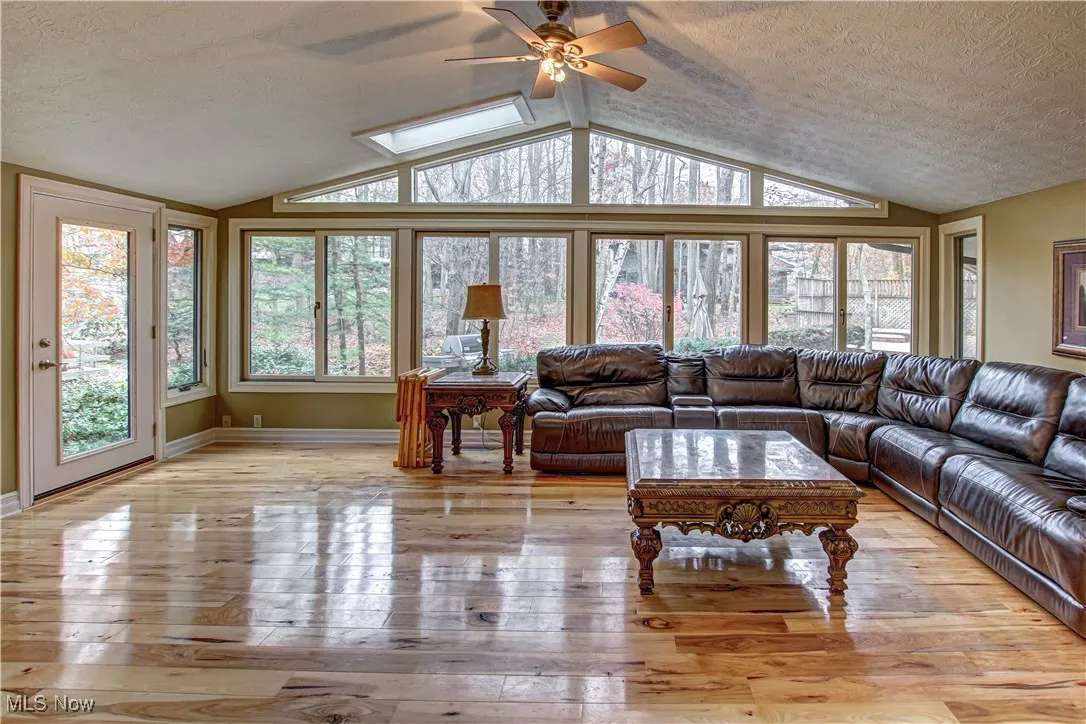 fireplace in corner, skylights, wall of windows, ceiling fan