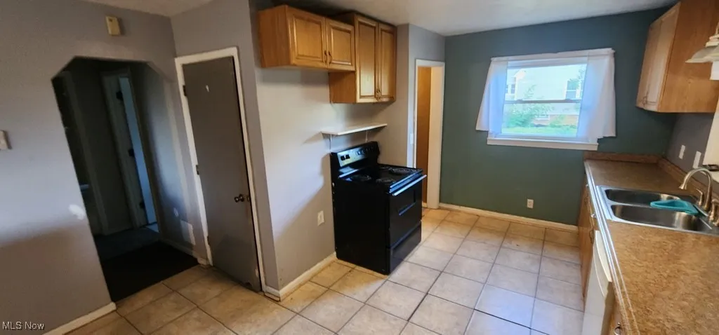 Kitchen featuring electric range, white dishwasher, light tile patterned flooring, and light countertops