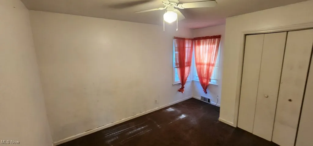 Unfurnished bedroom featuring a closet, a ceiling fan, and dark carpet