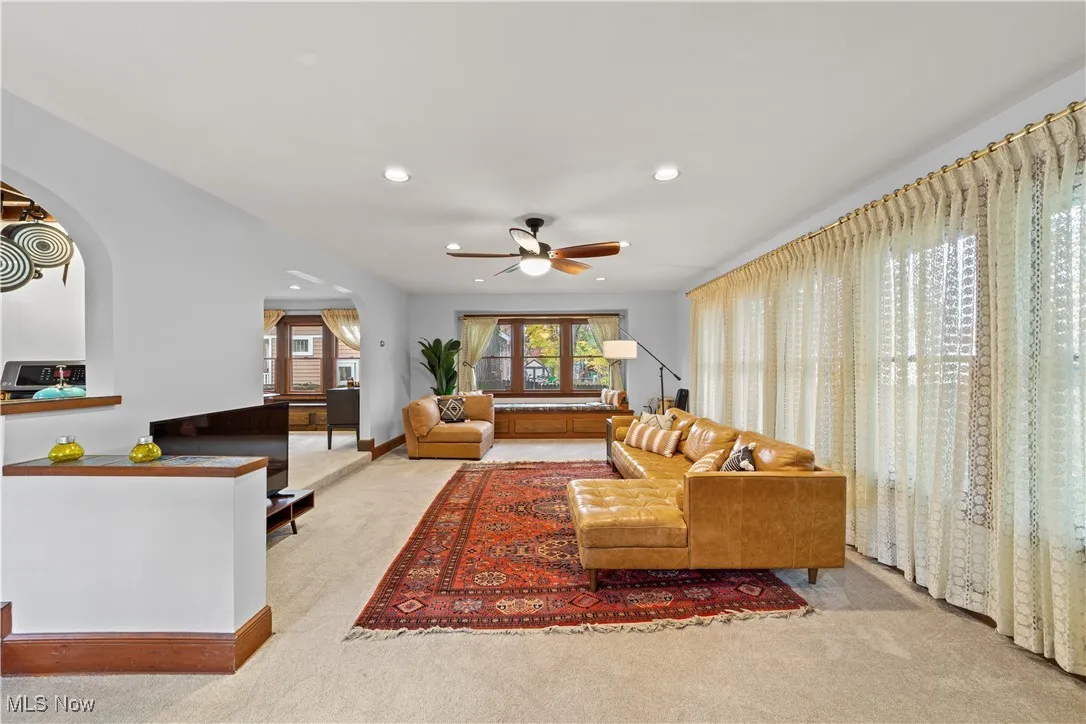 Living area featuring light colored carpet, recessed lighting, arched walkways, and a ceiling fan