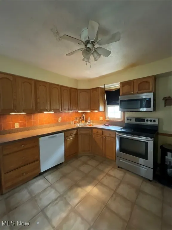 Kitchen featuring range, dishwasher, backsplash, a ceiling fan, and light countertops