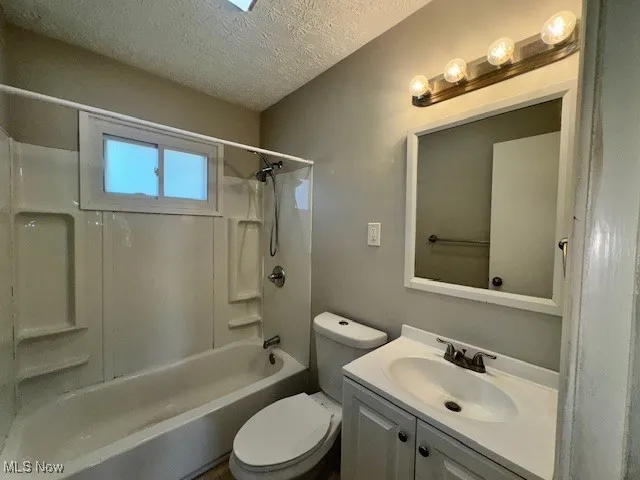 Full bathroom with a textured ceiling, washtub / shower combination, and vanity