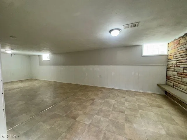 Basement featuring healthy amount of natural light, a wainscoted wall, and a textured ceiling
