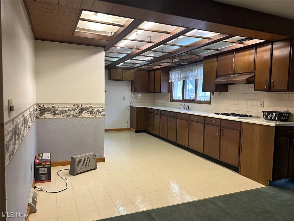 Kitchen featuring light countertops, dark brown cabinetry,