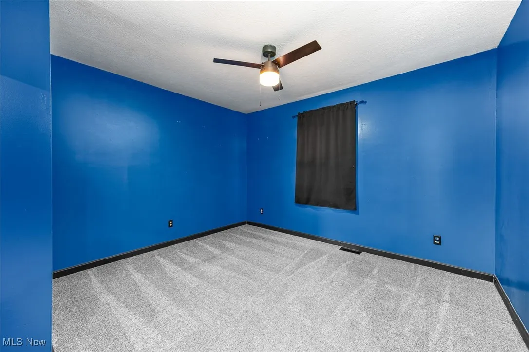 Spare room featuring carpet flooring, a textured ceiling, and a ceiling fan