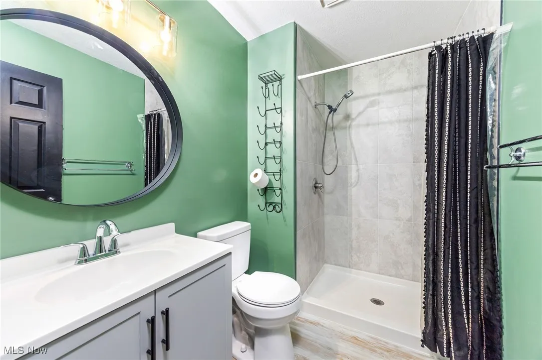 Bathroom featuring a shower stall, vanity, and wood finished floors