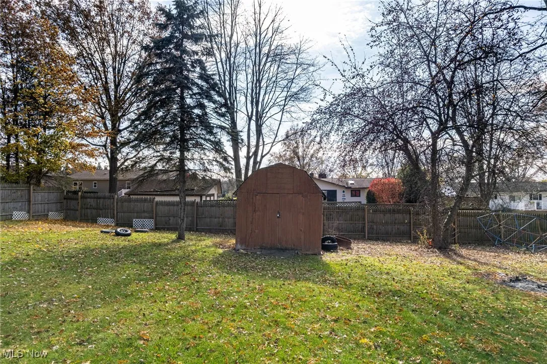 Fenced backyard featuring a storage shed
