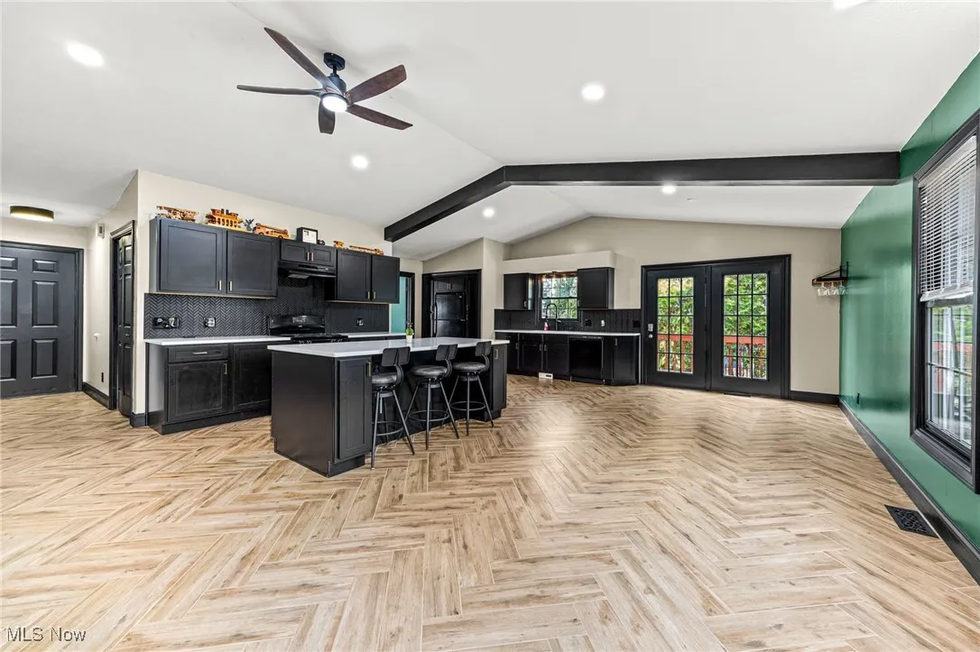 Kitchen with decorative backsplash, a kitchen breakfast bar, dark cabinetry, light countertops, and a kitchen island