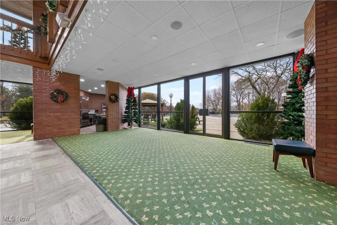 Lobby with brick wall, a wall of windows, a drop ceiling, and recessed lighting