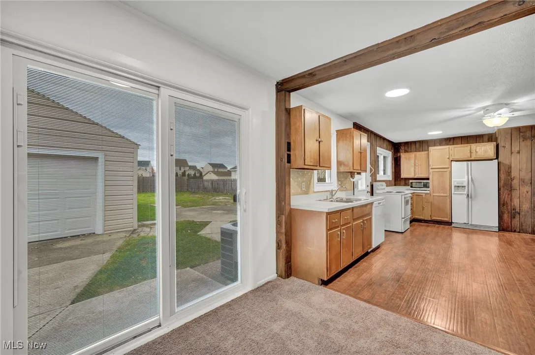 Kitchen with light countertops, white appliances, healthy amount of natural light, light carpet, and beam ceiling