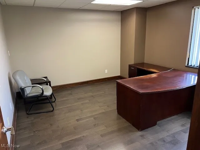 Office with a paneled ceiling and dark wood-style flooring