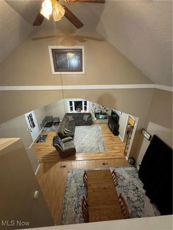 Bonus room with a textured ceiling, wood finished floors, a ceiling fan, and lofted ceiling
