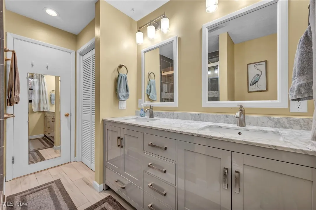Bathroom with a closet, double vanity, and light wood-style floors