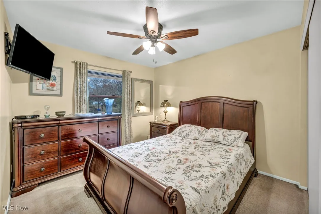 Bedroom with light colored carpet and a ceiling fan