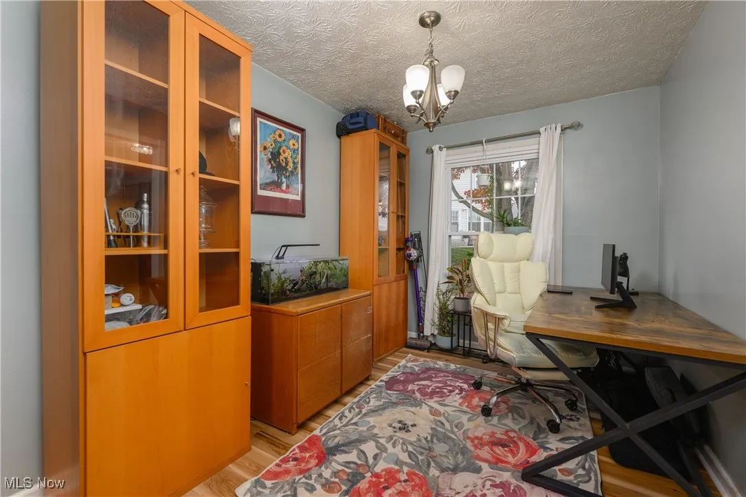 Office space featuring light wood-style floors, a textured ceiling, and a chandelier