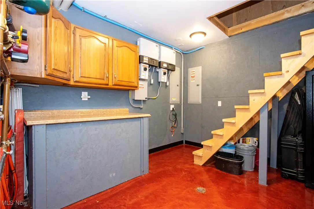 Below grade area with electric panel and stairway