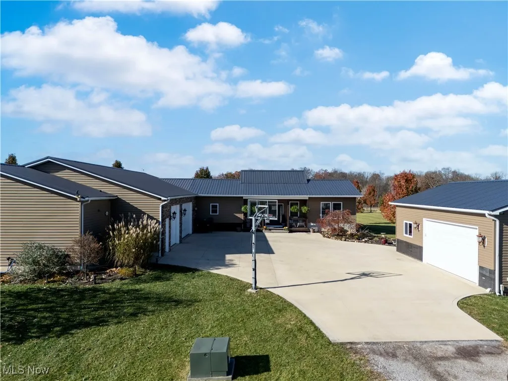 Ranch-style house with a front yard, a metal roof, and driveway