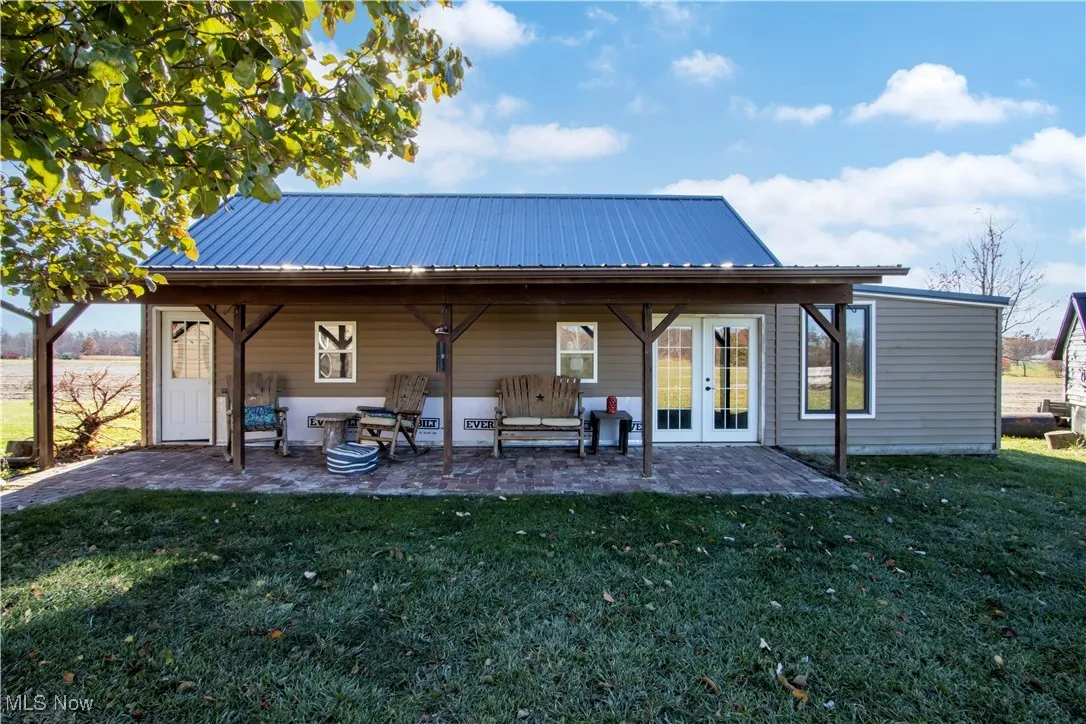 Rear view of house featuring a patio area, a yard, and a metal roof