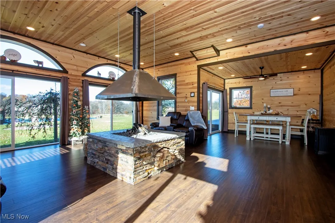 Living room featuring wooden ceiling, wood walls, recessed lighting, and dark wood finished floors