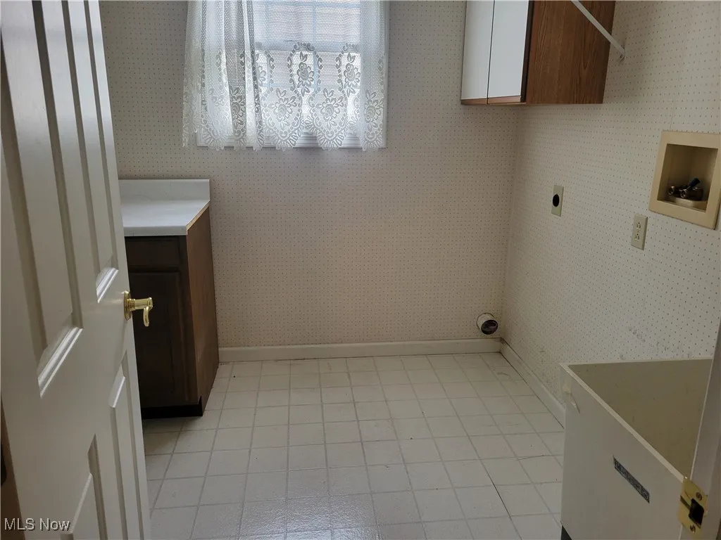 Washroom featuring cabinet space, hookup for a washing machine, electric dryer hookup, and wallpapered walls