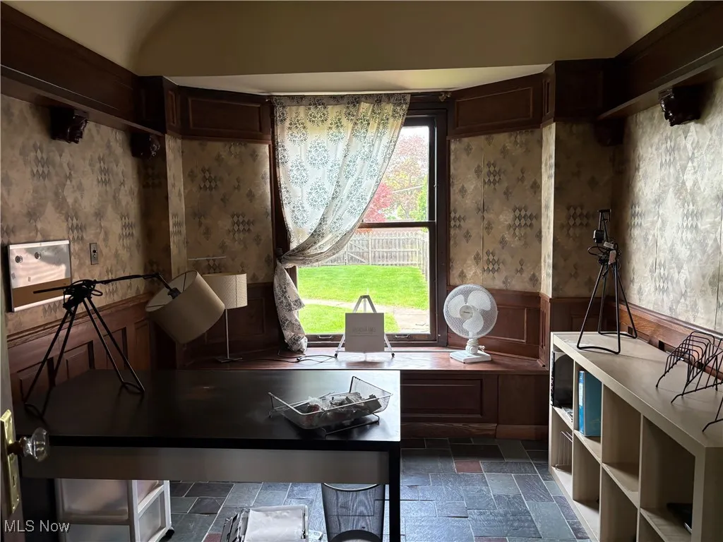 Miscellaneous room with stone tile flooring and a wainscoted wall