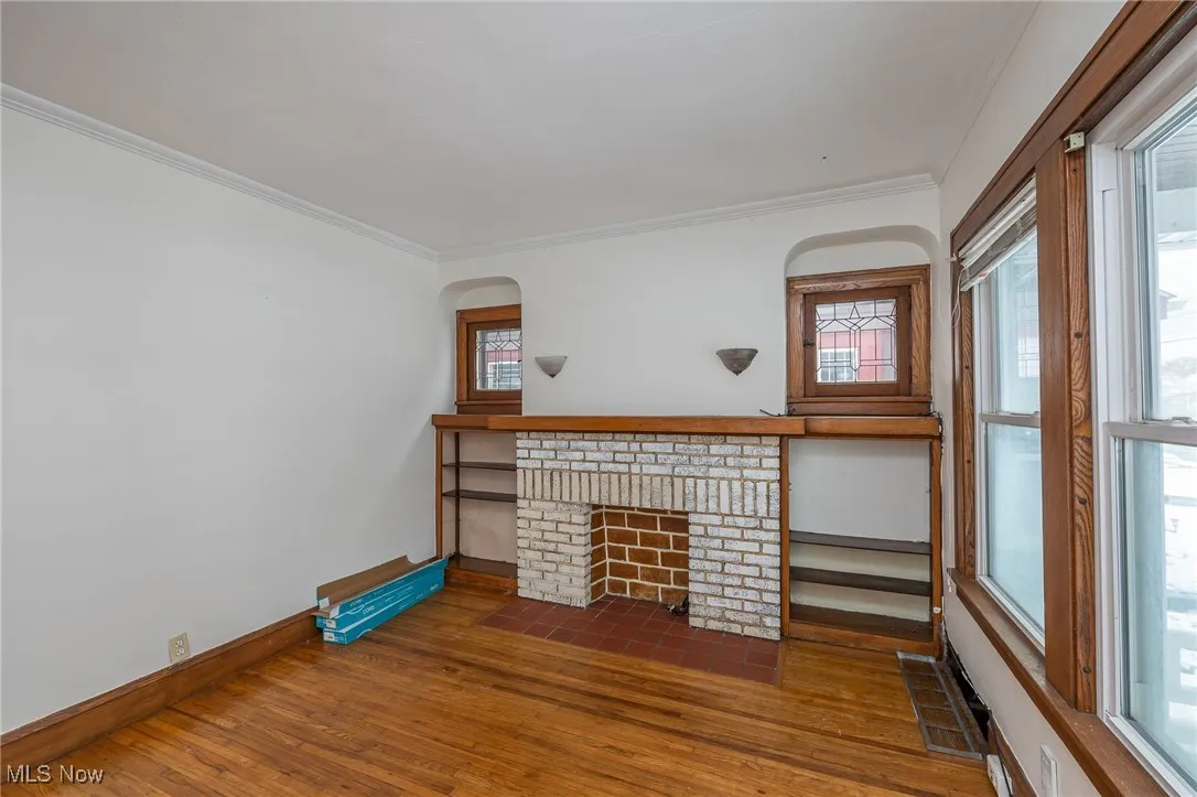 Living room with ornamental molding, hardwood floors, and a brick fireplace