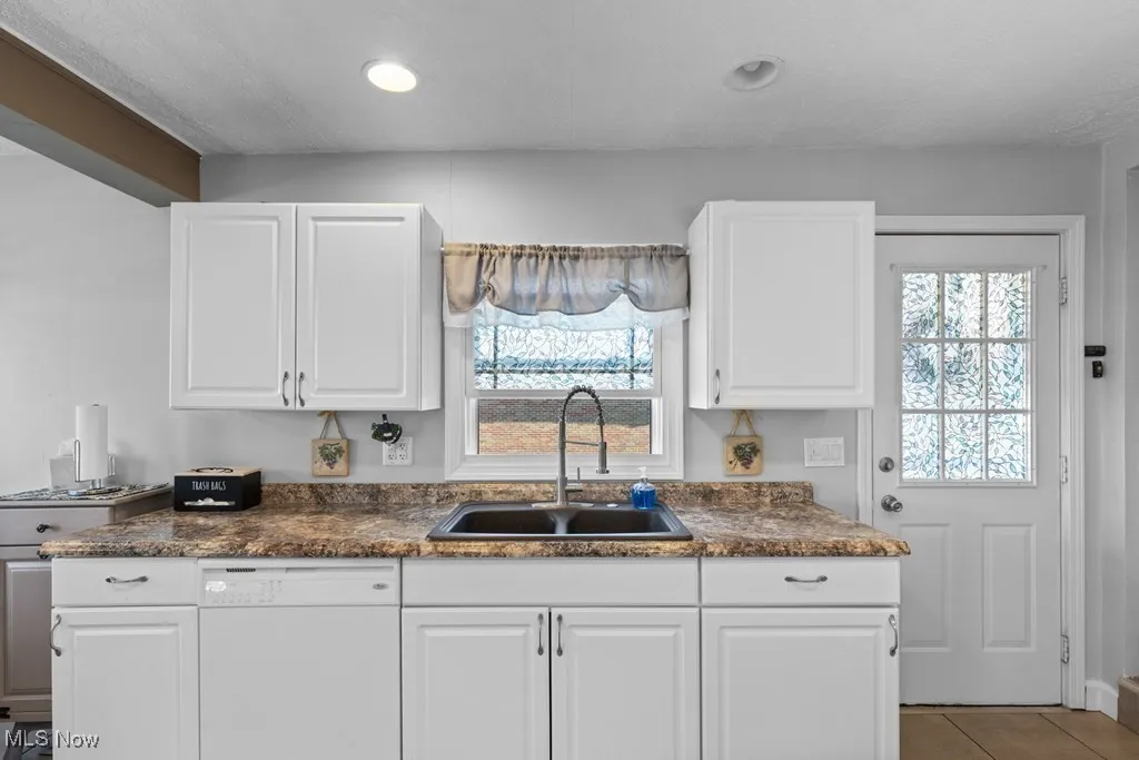 Kitchen featuring dishwasher, white cabinetry, recessed lighting, light tile patterned flooring, and dark stone counters