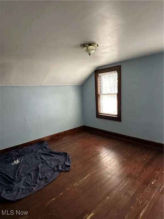 Bonus room with dark wood finished floors and lofted ceiling