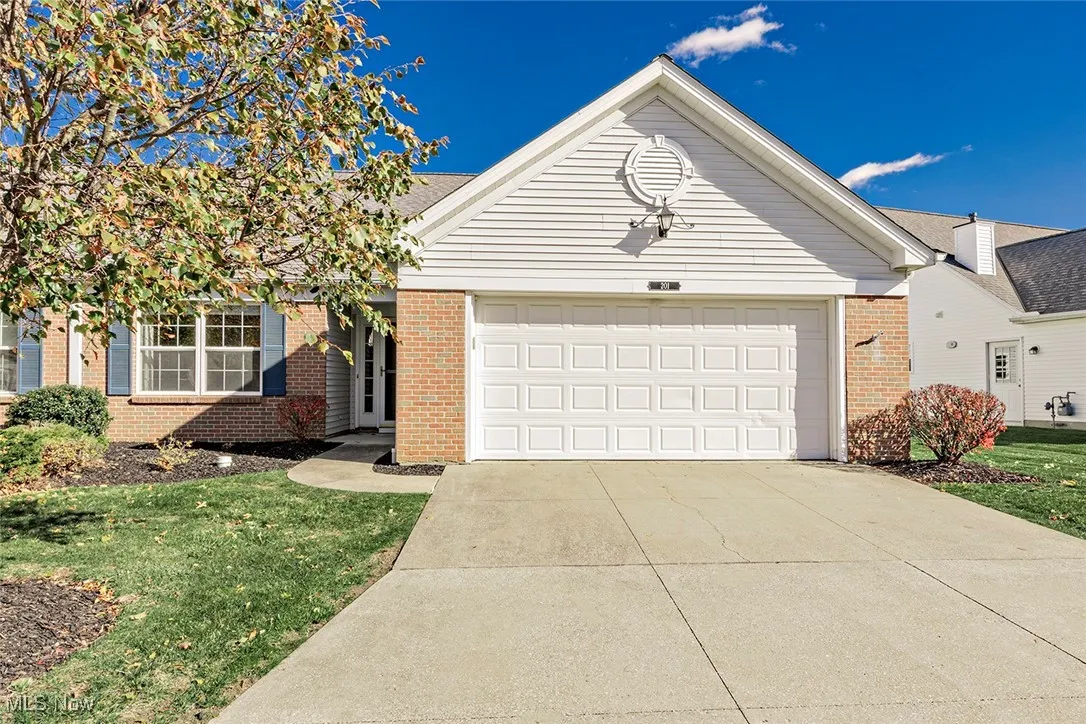 Ranch-style condominium featuring a garage, brick siding, concrete driveway.