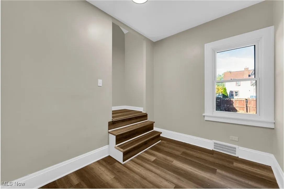 Spare room featuring dark wood-style floors and stairway