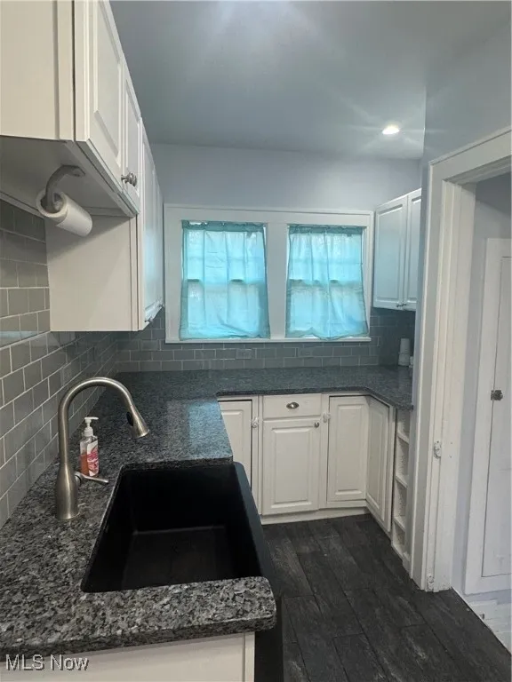 Kitchen featuring white cabinets, dark wood-type flooring, and dark stone counters